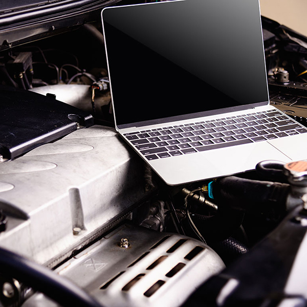 A laptop on a car engine, symbolizing websites for car garages and automotive services.