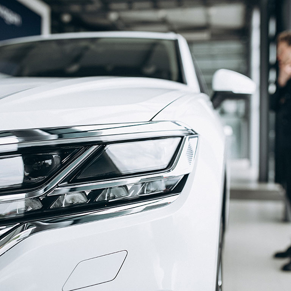 A man is next to a white car in a showroom, highlighting offerings for used car dealers and motor traders.